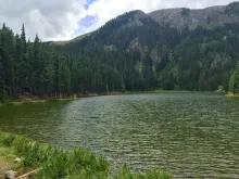 Middle Fork Lake above Red River, its forested shoreline backed by a rocky ridge in the Carson National Forest.